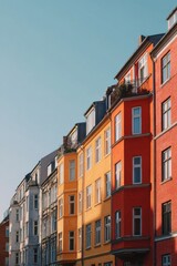 Fototapeta premium Vibrant, bright colors adorn the buildings lining a lively street, set against a clear blue sky in an urban area during the warm afternoon hours