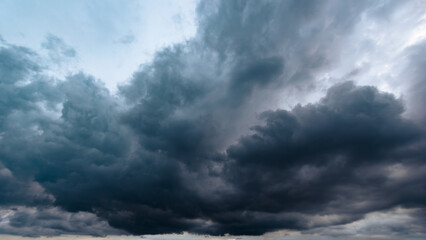 Obraz premium Massive dark storm clouds filling the sky before a heavy downpour, capturing an ominous and dramatic atmosphere perfect for themes of climate change and turbulent weather.