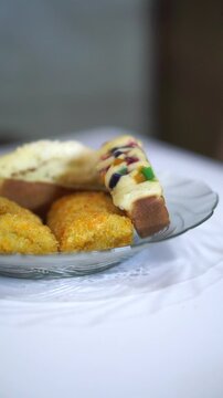 Assorted Indonesian traditional snacks featuring pukis cake and risoles served on a glass plate.