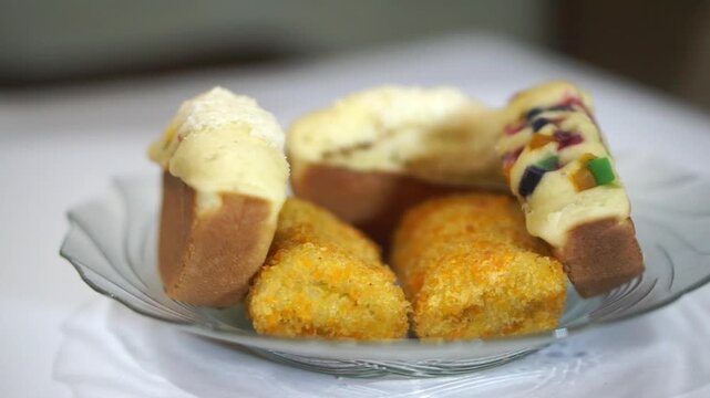 Assorted Indonesian traditional snacks featuring pukis cake and risoles served on a glass plate.