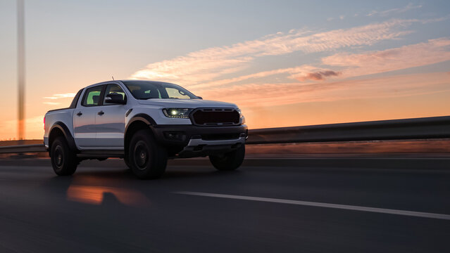 White pickup truck driving at sunset on highway road