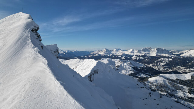 Aerial view of the snow-covered Aiguille Croche peak and the alpine mountain range under a clear blue sky in Les Contamines-Montjoie, Auvergne-Rhone-Alpes, France.