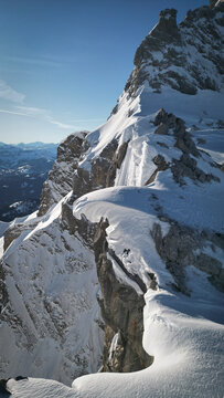 Aerial view of Pointe Percee with snow-covered mountain ridges and sharp rocky peaks under a clear blue sky in Le Reposoir, Auvergne-Rhone-Alpes, France.