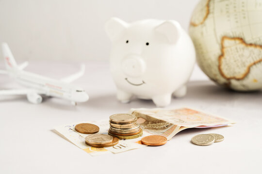 Travel savings with piggy bank, airplane, globe and cash money for vacation budget planning concept