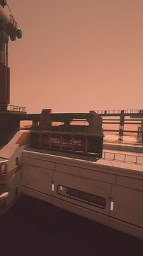 A structure stands with a red interior. The setting sun casts an orange glow over the scene. The building has a distinct design and features numerous levels and edges.