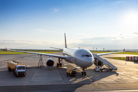 Wide body passenger airplane with boarding stairs at the airport. Airfield tanker refueling plane