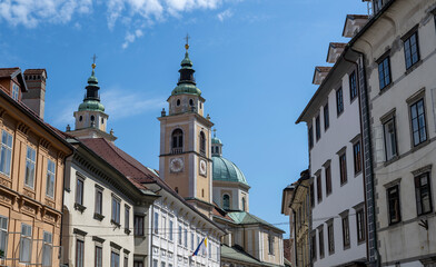 Fototapeta premium Historic church towers and old architecture in Ljubljana city center under blue sky with sunny weather and classic European urban scenery
