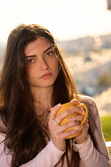 Fototapeta premium Young woman enjoying coffee outdoors in sunlight