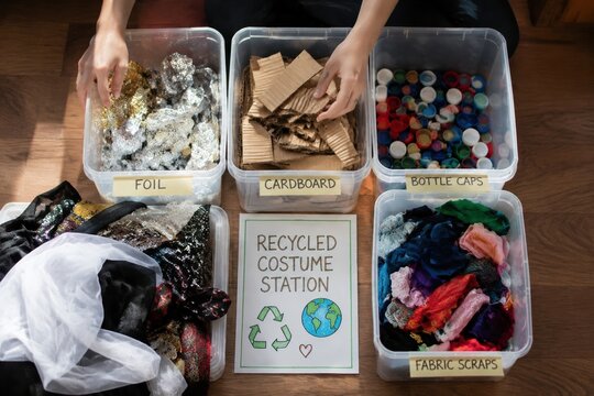 Hands sorting cardboard, foil, bottle caps, and fabric scraps into bins. This station promotes eco-friendly creativity and sustainable waste management. Ideal for educational or environmental content.