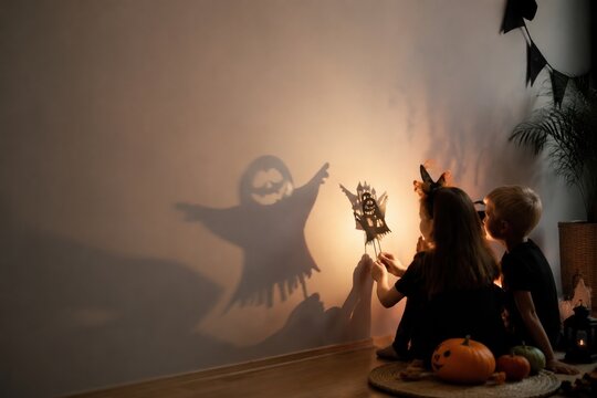 Children play with shadow puppets of a ghost and haunted house. Warm home atmosphere during Halloween holiday. Perfect for family celebrations and festive marketing materials.