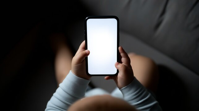 Baby sitting on sofa holding smartphone, blank screen presenting opportunity for content, learning, or early digital interaction