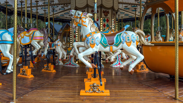 Classic carousel horses with ornate details on a wooden platform at an amusement park