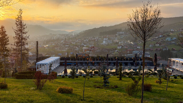 Mountain resort town at sunrise with infinity pool and lush green landscape