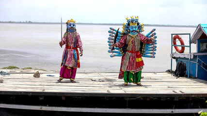 Naklejka premium Traditional Masked Performers Dancing on Riverside Boat, Majuli Mukha Shilpa