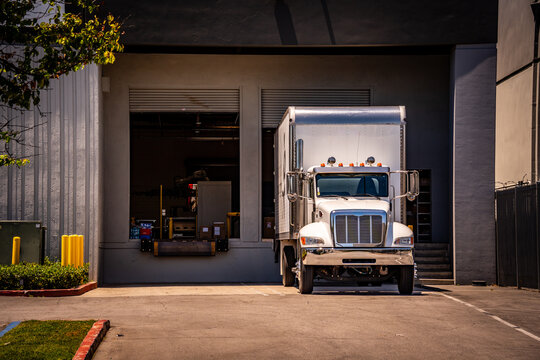 White semi-truck parked at a loading dock in a commercial warehouse