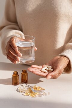 Elderly hands holding supplements and a glass of water for daily health routine and medication management background for healthcare design