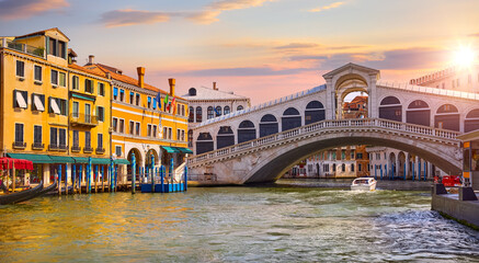 Venice, Italy. Rialto Bridge on Grand canal of Venezia. Famous landmark panoramic view of venice with sunset evening sky white clouds, boats and gondolas on water. © Yasonya