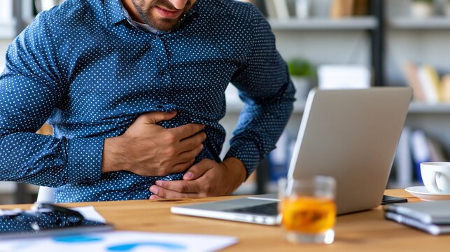Man Experiences Stomach Ache While Working in Office Setting During Daytime Hours, Highlighting Digestive Problems in a Business Environment