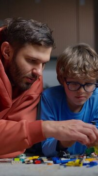 A father and son engaged in a focused and creative activity building with colorful small construction blocks on a table indoors, fostering learning and bonding time together