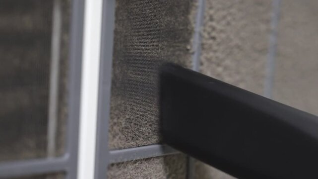 Black vacuum cleaner brush attachment removing thick dust from dusty fabric window screen mesh indoor, household cleaning routine and home maintenance concept.