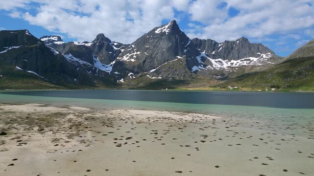 Breathtaking panorama of Morpheus beach in the Lofoten Islands, featuring majestic snow capped mountains reflecting in the calm turquoise fjord