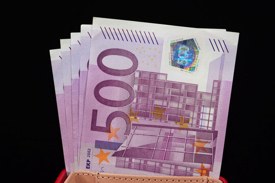 A red wallet containing five 500 Euro banknotes, totaling 2500 Euros, representing financial independence and wealth accumulation