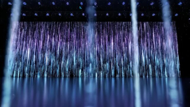 Abstract blue digital rain animation on a large LED stage screen. Futuristic technology background with falling data streams and reflections on the floor