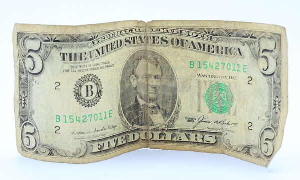 Old torn faded five dollar bills banknotes. US currency cash. White background. Abraham Lincoln.