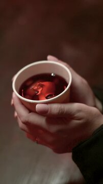 Close Up Hands Holding Hot Mulled Wine Cup in Winter Christmas Market