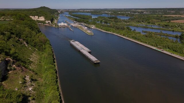 Exploring the river lock on the Maas at Ecluse de Lanaye near the border of Belgium and the Netherlands with a passing barge