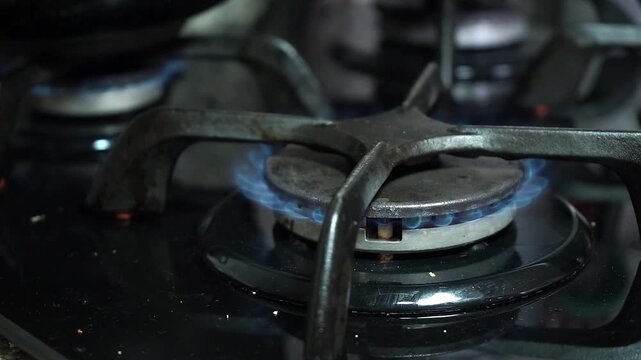 Close up of a gas stove burner igniting with a blue flame on a kitchen cooktop