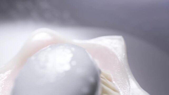 Tracking shot macro close up of brush head spreading thick white foam across bristles on glossy ceramic surface