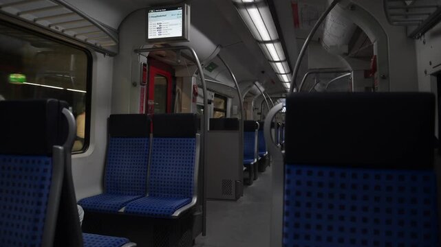 Stuttgart, Germany - 19.05.2026: Quiet regional train carriage interior with blue seats, handrails, and onboard information screen.