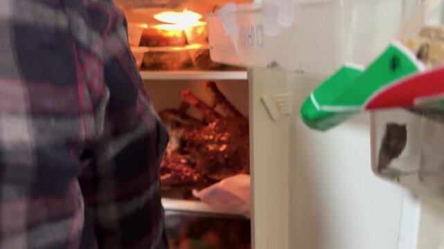 Man&rsquo;s placing a live king crab into a small household refrigerator for Lunar New Year preparations at home in China. Everyday domestic scene capturing festive food traditions, seafood preparation, and