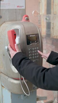 Close Up Hand Using Vintage Public Telephone and Dialing Number