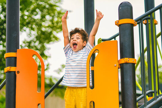 Happy kid on playground on summer season hand up