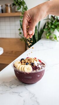 Hand Sprinkling Granola on a Healthy A&ccedil;ai Smoothie Bowl