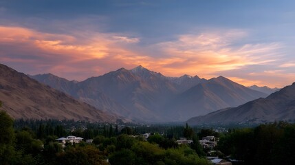 Obraz premium Dramatic sunset or sunrise paints the vast mountain landscape with vibrant orange pink and blue hues over a lush valley