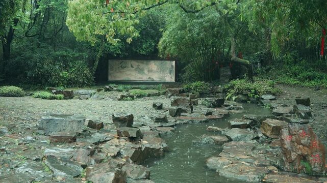 Rainy day park landscape with rocky stream and green trees