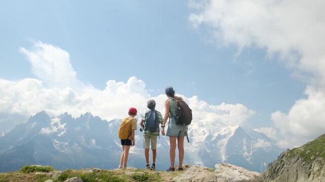 Adventurous mother and her two children hiking together while enjoying the breathtaking mountain landscape of mont blanc, chamonix, france, during a summer vacation