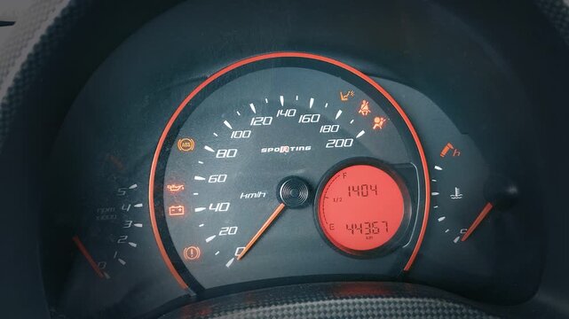 Car dashboard speedometer showing vehicle speed and warning lights illuminating on the digital instrument cluster.
