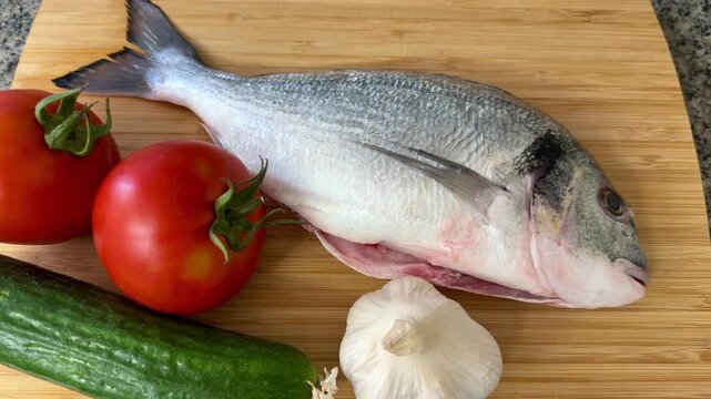 Raw sea bream fish with vegetables. A close-up shot of raw fish, cooking delicious food at home.