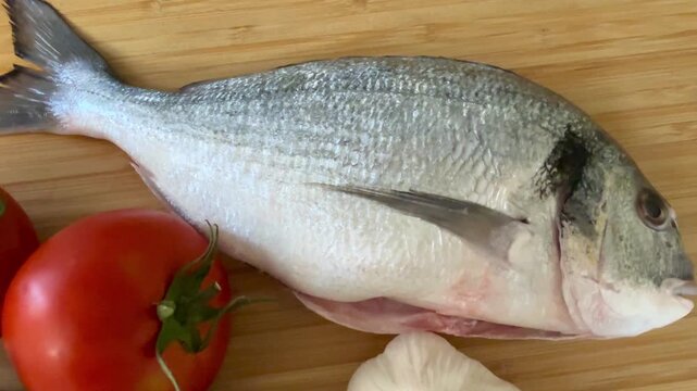 Raw sea bream fish with vegetables. A close-up shot of raw fish, cooking delicious food at home.
