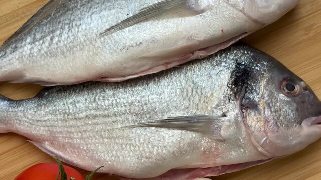 Two raw sea bream fish with vegetables. A close-up shot of raw fish, cooking delicious food at home.