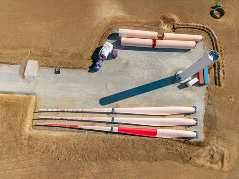 Aerial view of wind turbine blades and tower sections at a construction site on dry land Swellendam, Western Cape, South Africa.