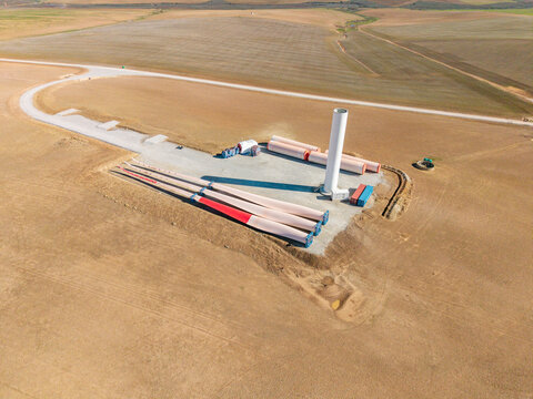 Aerial view of wind turbine components including a tower section and blades at a construction site in a rural landscape Swellendam, Western Cape, South Africa.
