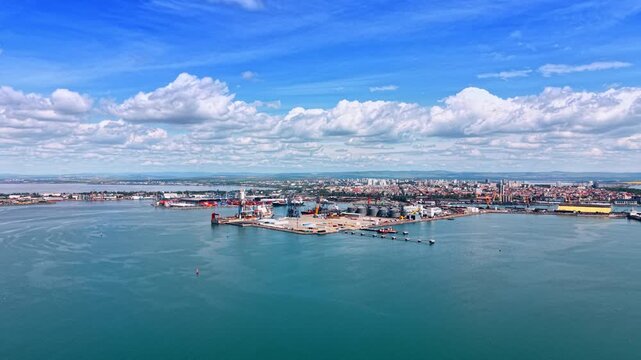 Footage over vast marina with a port facility on. Modern cityscape under the cloudy sky in the backdrop.