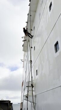team work of international seafarers. ship crew working aloft for paint ship forward bulkhead of superstructure. performing this job possible only with good cooperation and organization of process.