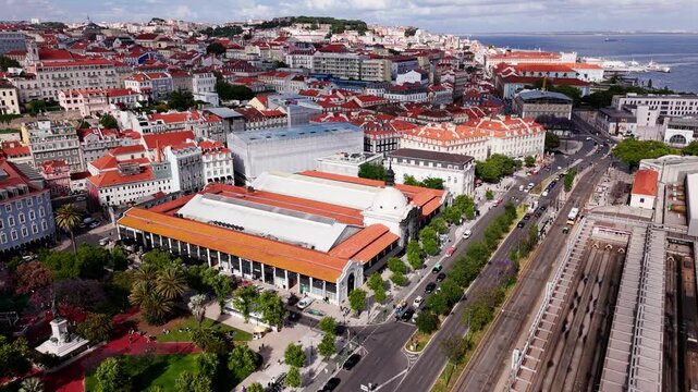 Aerial view of Lisbon cityscape. Timeout Market, railroad paths, red-roofed buildings under cloudy sky