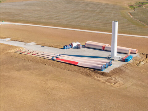 Aerial view of wind turbine components including blades and tower base at a construction site in a rural landscape Swellendam, Western Cape, South Africa.